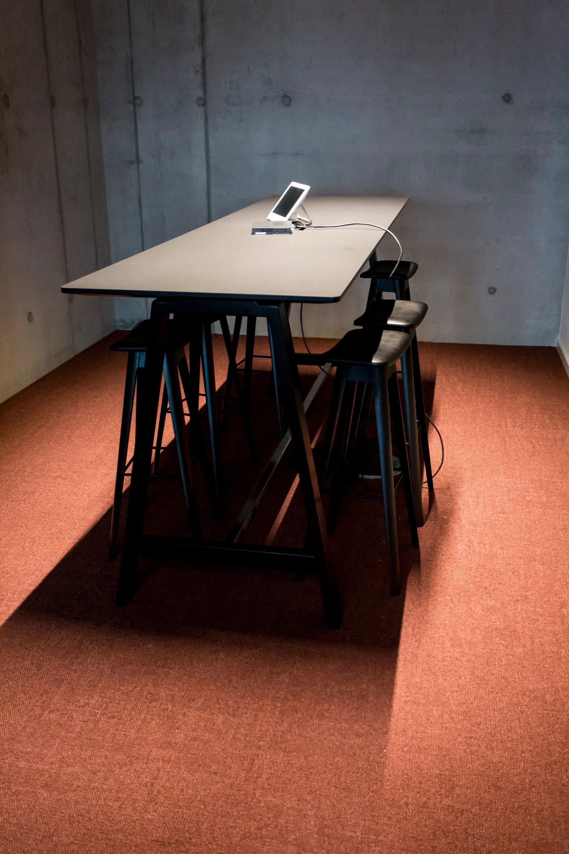 Stehtisch mit Hockern vor einer Betonwand