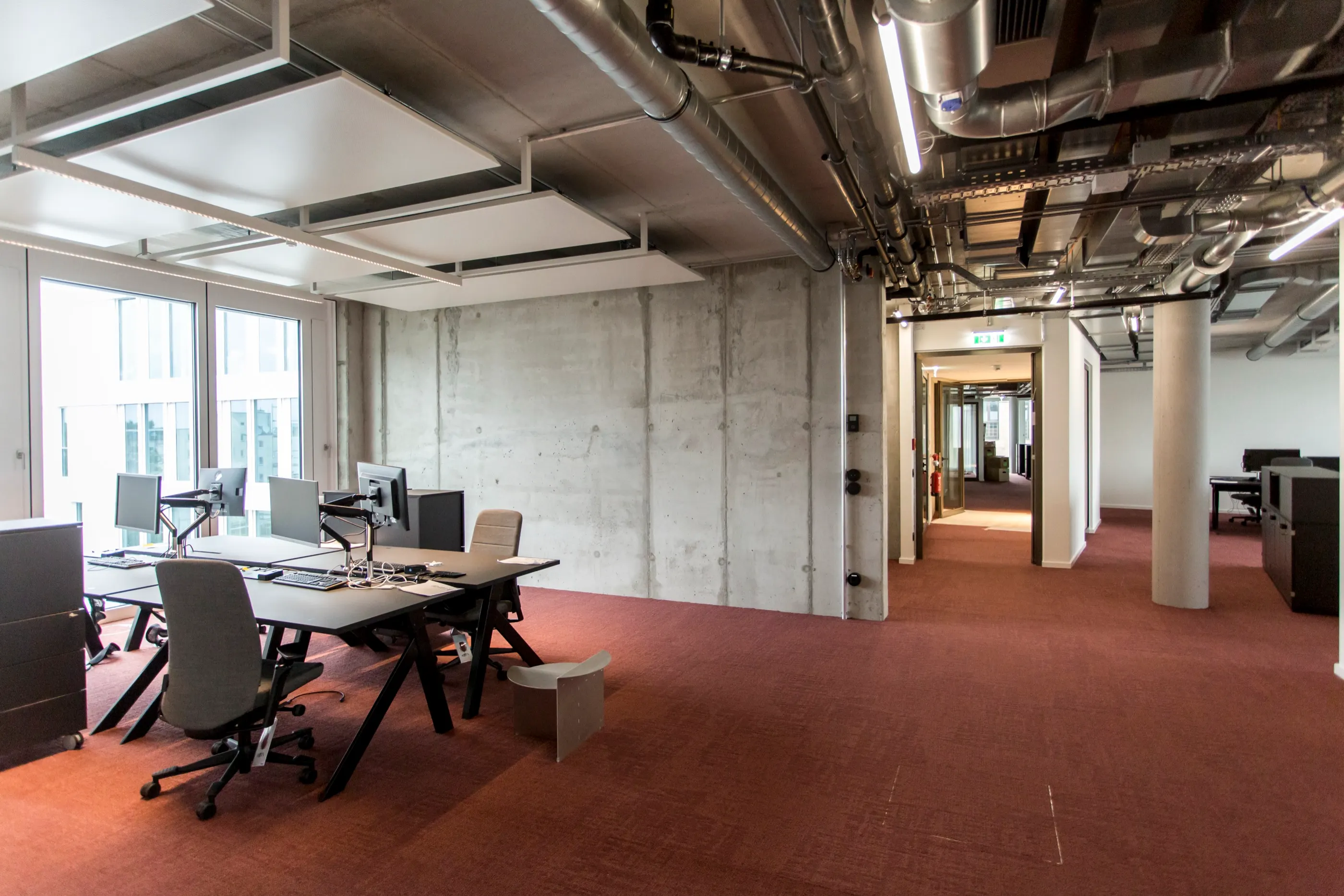 Open-Space-Fläche mit sichtbarer Haustechnik und Betonwand