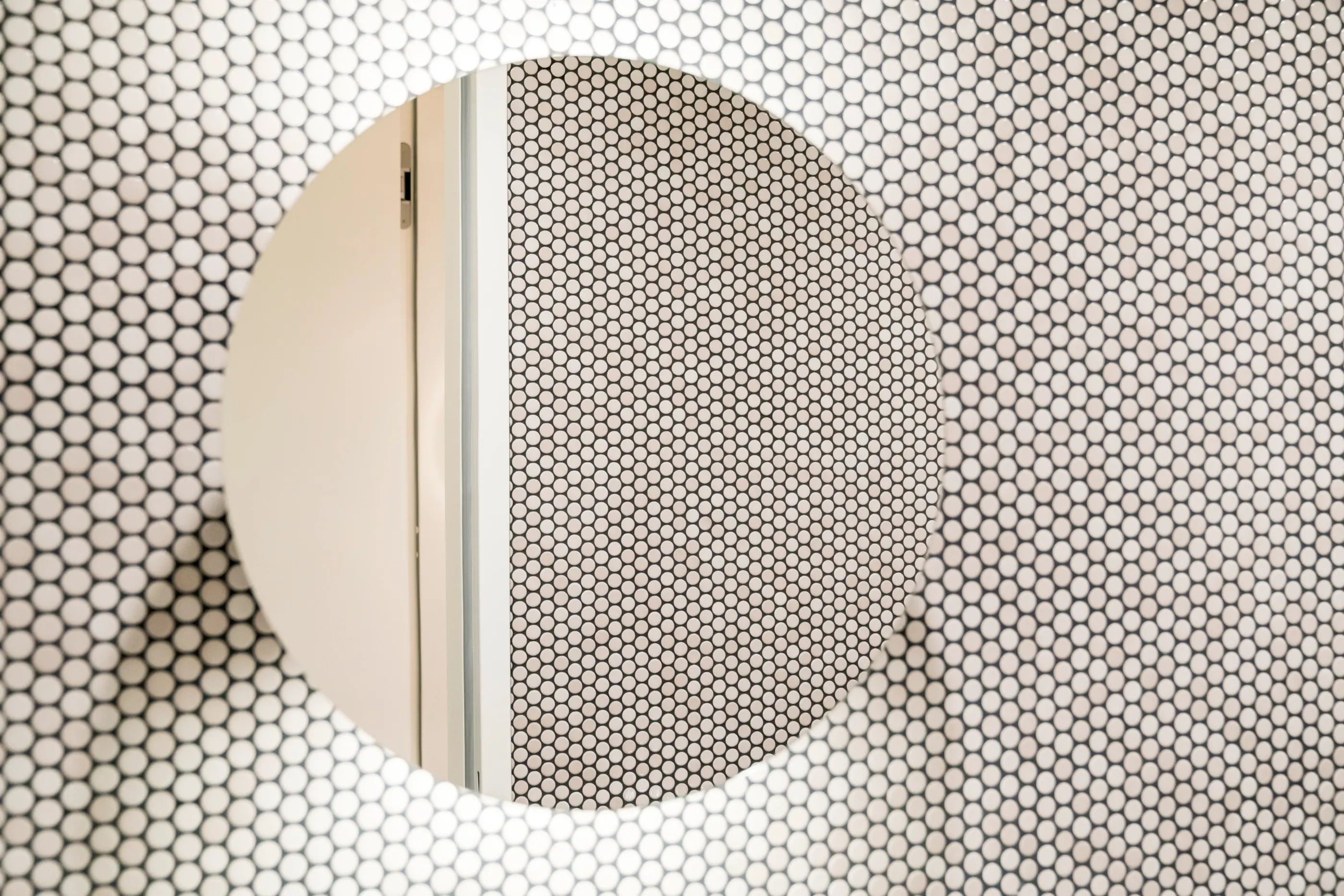 Runder Spiegel auf einer Wand aus weißem Mosaikfliesen-Raster