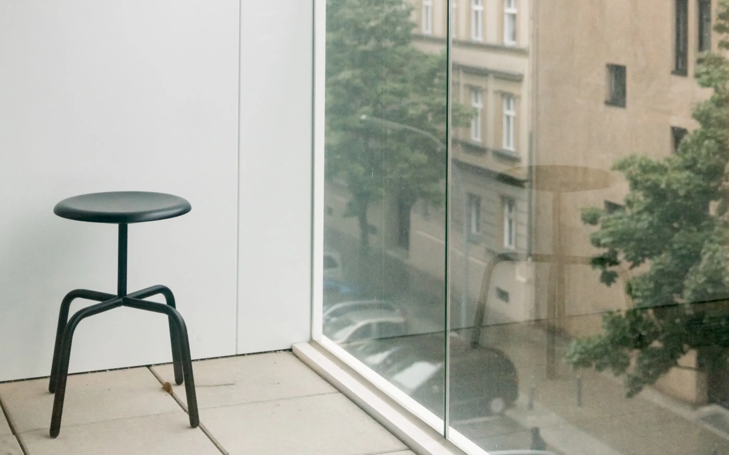 Hocker an der Fensterfront, dahinter die Straße durch die Verglasung