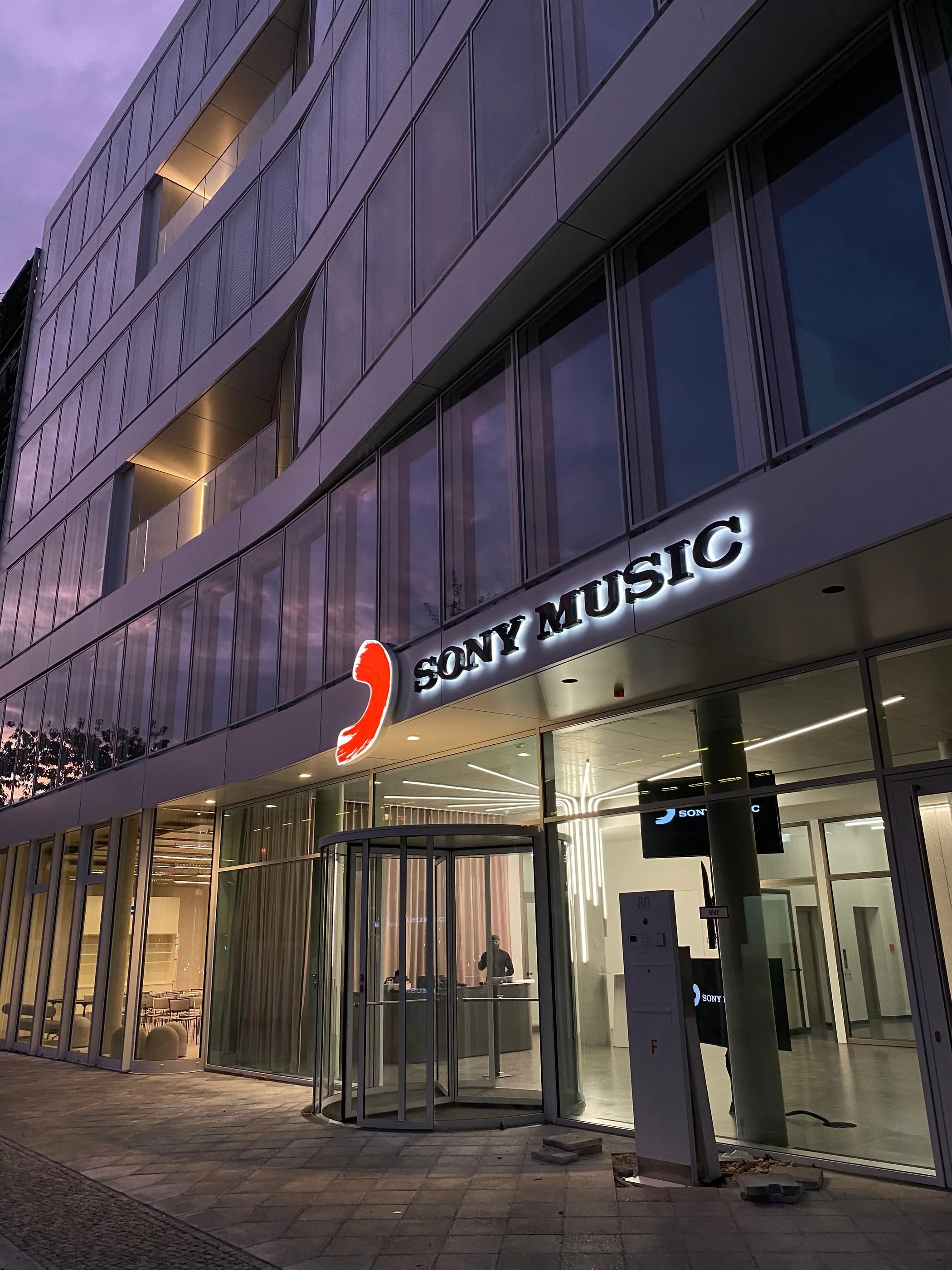 Fassade des Sony-Music-Gebäudes in der Abenddämmerung mit beleuchtetem Logo